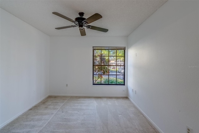 unfurnished room with ceiling fan, baseboards, a textured ceiling, and light colored carpet