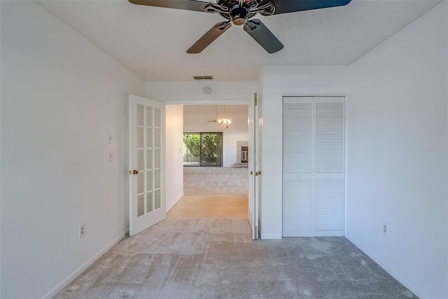 carpeted empty room featuring french doors, visible vents, ceiling fan, and baseboards