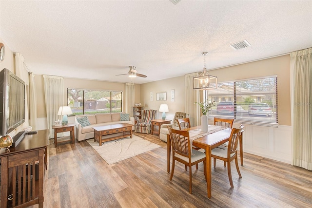 2546 Oakleaf Ln Unit 35D, Clearwater, FL 33763 - dining space featuring a textured ceiling, wood finished floors, ceiling fan, a wainscoted wall, and a chandelier