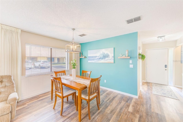 2546 Oakleaf Ln Unit 35D, Clearwater, FL 33763 - dining space with light wood finished floors, a textured ceiling, a chandelier, and baseboards