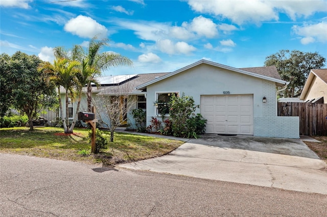 single story home with a garage, a front yard, and solar panels