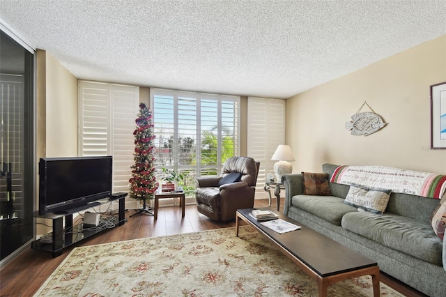 living room with dark wood-type flooring, a textured ceiling, and a wall of windows