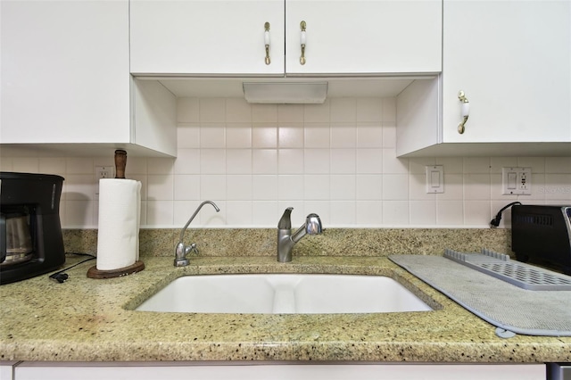 kitchen with white cabinetry, sink, tasteful backsplash, and light stone countertops