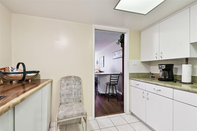 kitchen featuring tasteful backsplash, light tile patterned floors, and white cabinets