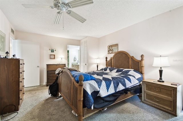 bedroom with ceiling fan, ensuite bath, carpet floors, and a textured ceiling