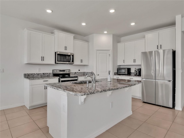 kitchen featuring sink, appliances with stainless steel finishes, a kitchen island with sink, white cabinetry, and stone countertops