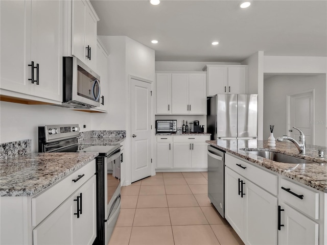 kitchen featuring stainless steel appliances, light stone countertops, sink, and white cabinets