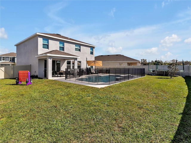 rear view of house with a fenced in pool, a patio area, and a lawn