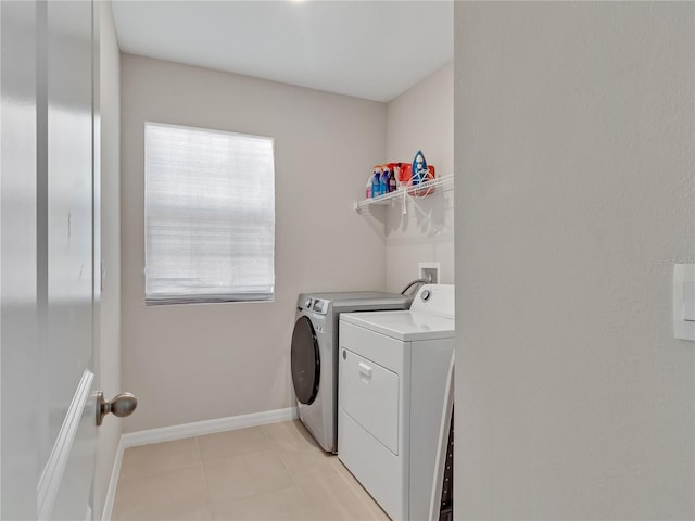 clothes washing area featuring light tile patterned floors and washer and clothes dryer