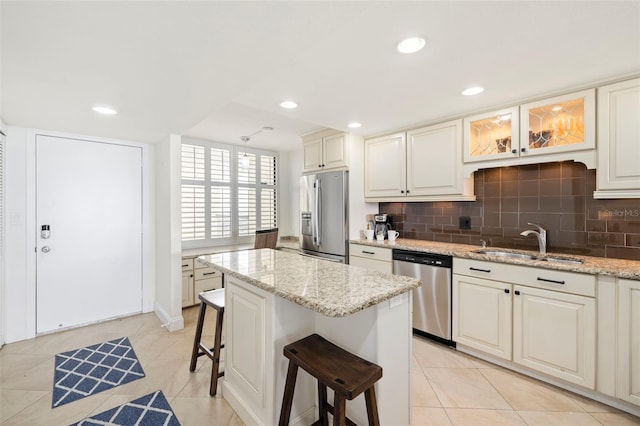 kitchen featuring light stone countertops, appliances with stainless steel finishes, sink, and a breakfast bar area