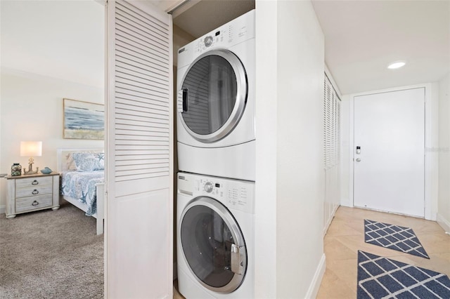 laundry room featuring stacked washer and clothes dryer and light tile patterned floors