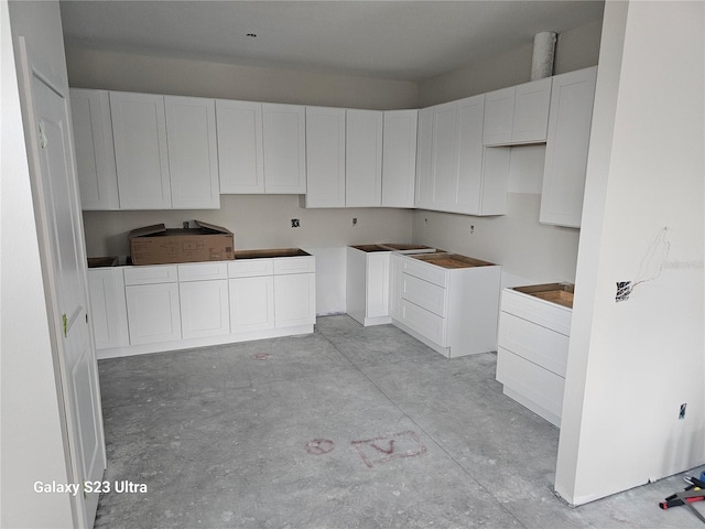 kitchen with white cabinets and unfinished concrete flooring