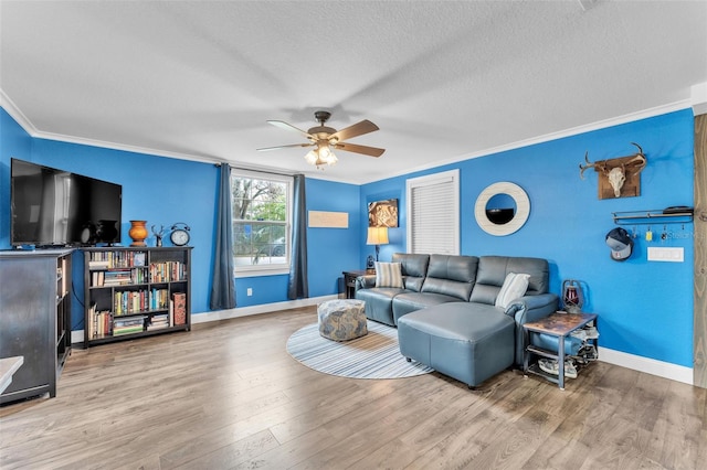 living room featuring crown molding, ceiling fan, hardwood / wood-style flooring, and a textured ceiling