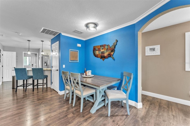 dining space with crown molding, dark wood-type flooring, and a textured ceiling