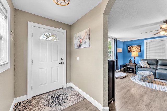 foyer with ceiling fan, a textured ceiling, and light wood-type flooring