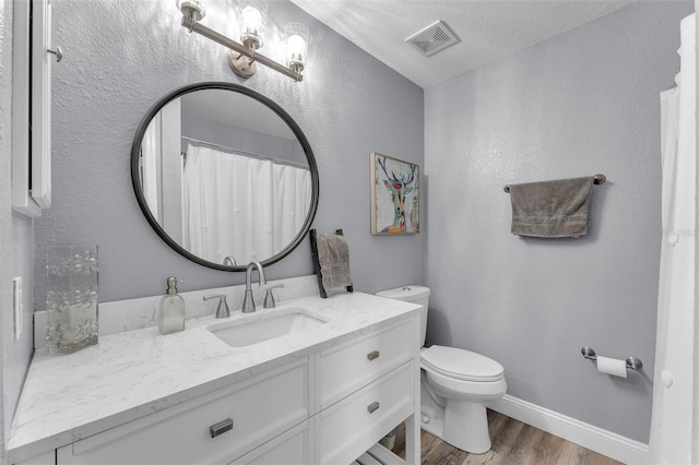 bathroom featuring vanity, toilet, hardwood / wood-style floors, and a textured ceiling