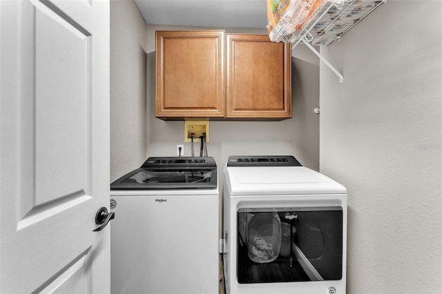 laundry room featuring washer and clothes dryer and cabinets