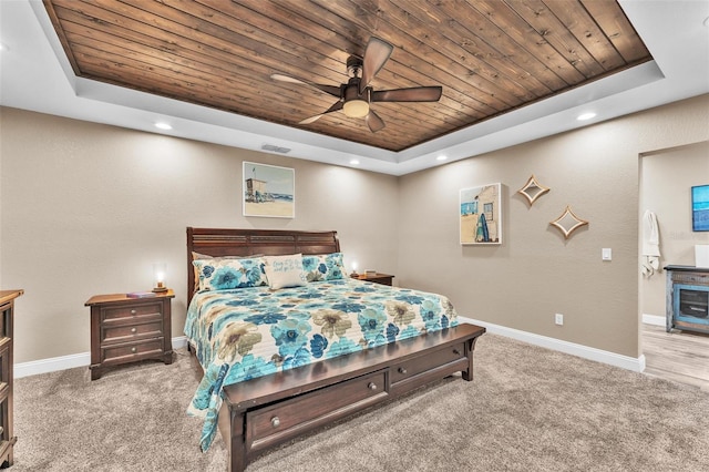 bedroom with ceiling fan, carpet, wood ceiling, and a tray ceiling