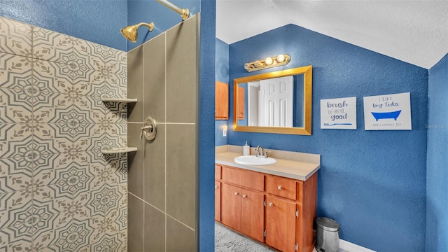 bathroom with vanity, vaulted ceiling, and a tile shower