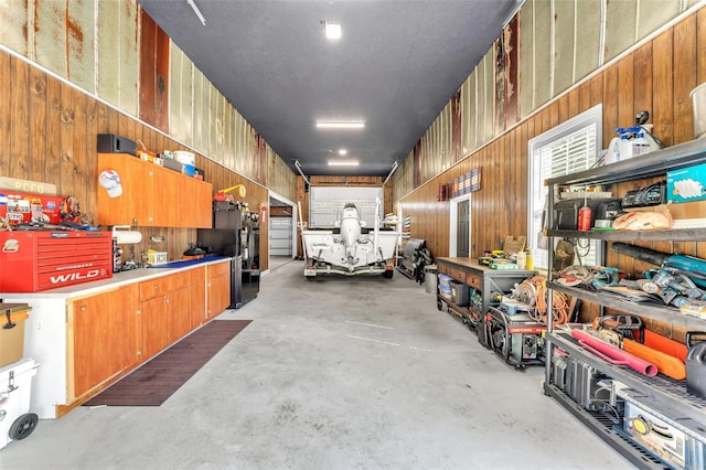 garage with black fridge, wood walls, and a workshop area