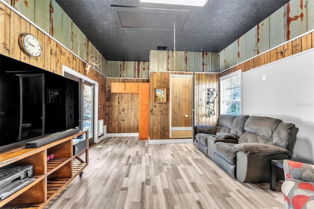 living room featuring wooden walls, light hardwood / wood-style floors, and a textured ceiling