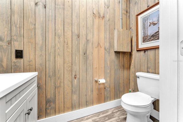 bathroom with vanity, wood-type flooring, wooden walls, and toilet