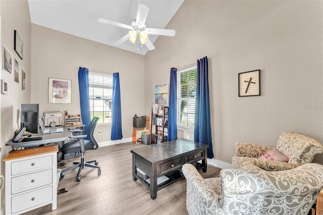 office featuring ceiling fan, high vaulted ceiling, and light wood-type flooring