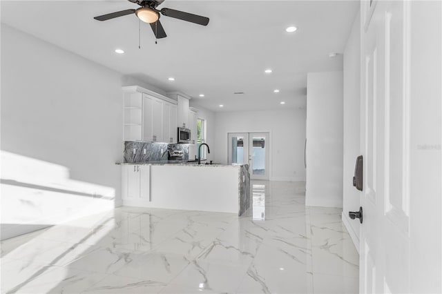 kitchen with white cabinetry, sink, dark stone countertops, decorative backsplash, and stainless steel appliances