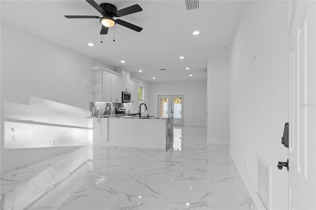 interior space featuring french doors, sink, stone countertops, kitchen peninsula, and white cabinets