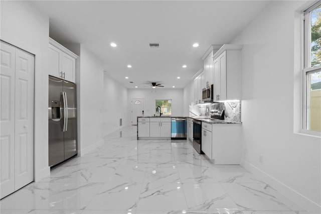 kitchen with appliances with stainless steel finishes, a wealth of natural light, sink, white cabinets, and kitchen peninsula