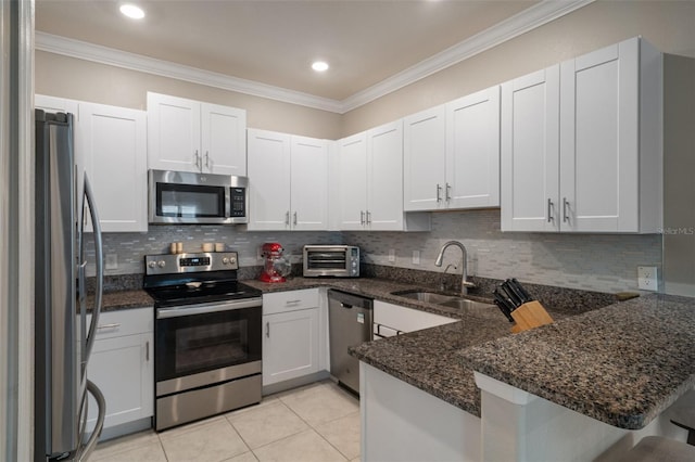 kitchen featuring appliances with stainless steel finishes, sink, dark stone countertops, white cabinets, and kitchen peninsula