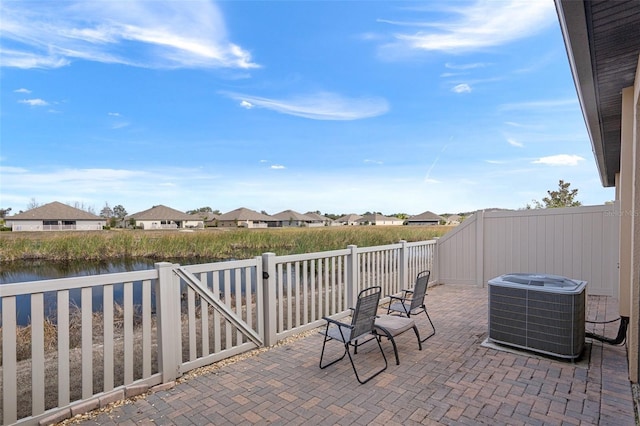 view of patio featuring a water view and cooling unit