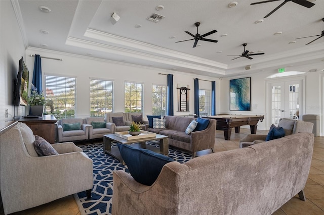 living room featuring french doors, plenty of natural light, a raised ceiling, and light tile patterned floors