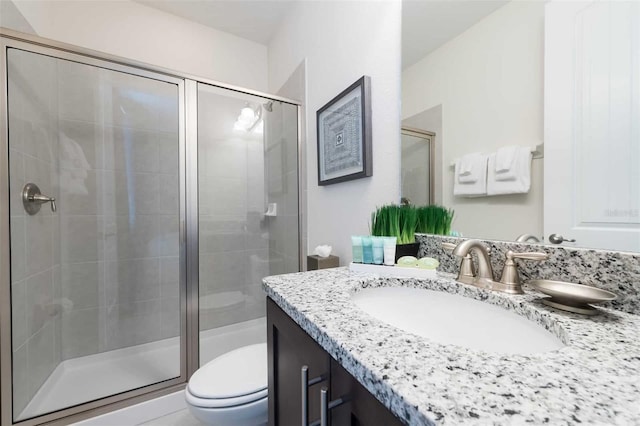 bathroom with vanity, a shower with door, and toilet