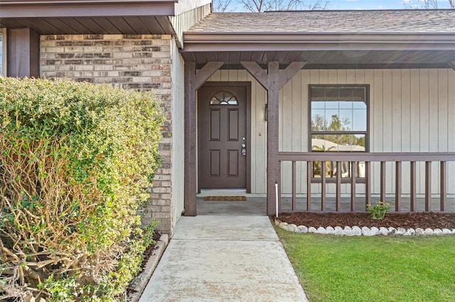 view of exterior entry with covered porch and a lawn