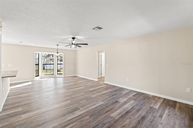 unfurnished living room featuring hardwood / wood-style flooring, ceiling fan with notable chandelier, and a textured ceiling