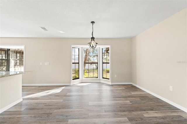 unfurnished dining area with hardwood / wood-style floors and a textured ceiling