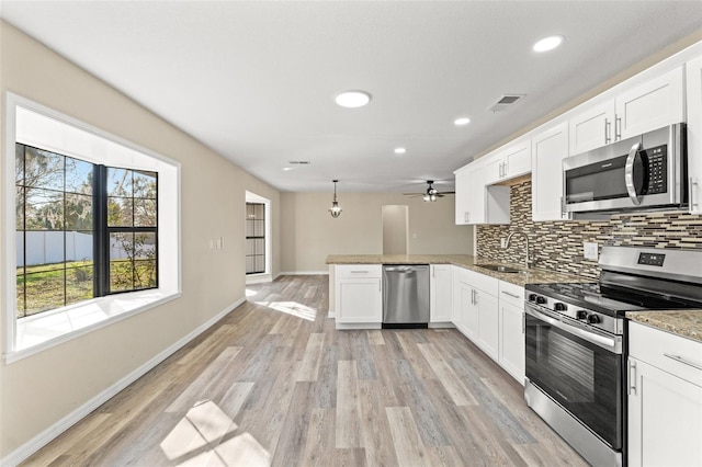 kitchen with sink, hanging light fixtures, stainless steel appliances, white cabinets, and kitchen peninsula