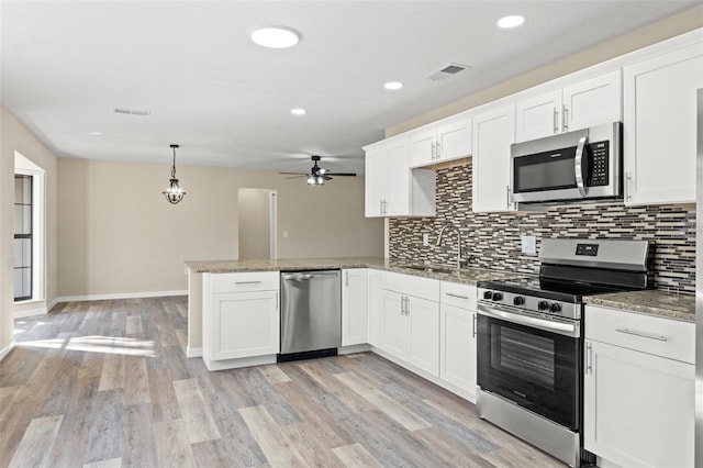 kitchen with pendant lighting, appliances with stainless steel finishes, kitchen peninsula, and white cabinets