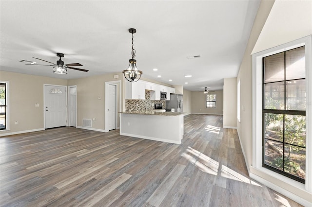 kitchen with white cabinetry, appliances with stainless steel finishes, ceiling fan with notable chandelier, and decorative backsplash