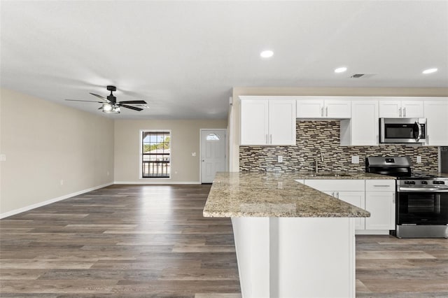 kitchen with sink, appliances with stainless steel finishes, backsplash, light stone countertops, and white cabinets