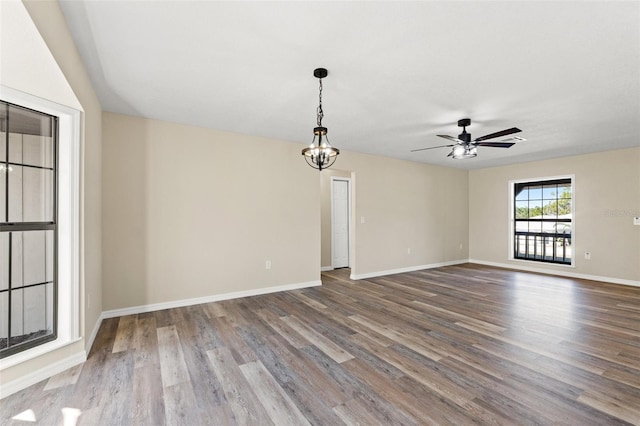 spare room featuring hardwood / wood-style floors and ceiling fan with notable chandelier