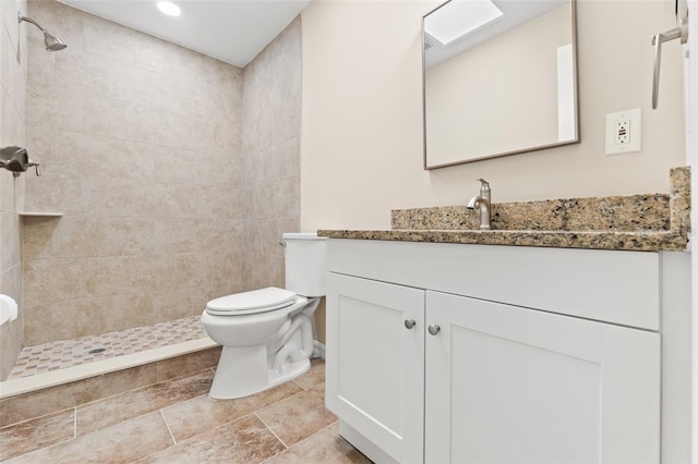 bathroom featuring vanity, toilet, and a tile shower