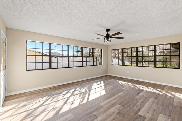 unfurnished room with a textured ceiling, light hardwood / wood-style floors, and ceiling fan