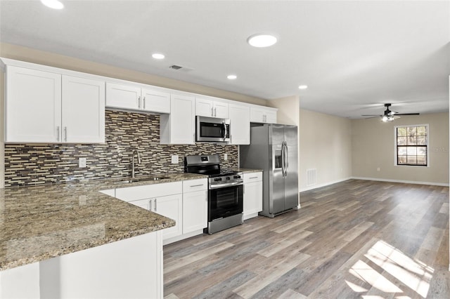 kitchen featuring appliances with stainless steel finishes, stone countertops, white cabinetry, sink, and backsplash