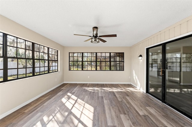 empty room featuring ceiling fan, wood-type flooring, and a textured ceiling