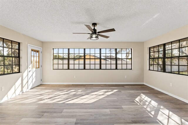 empty room with ceiling fan, light hardwood / wood-style flooring, and a textured ceiling