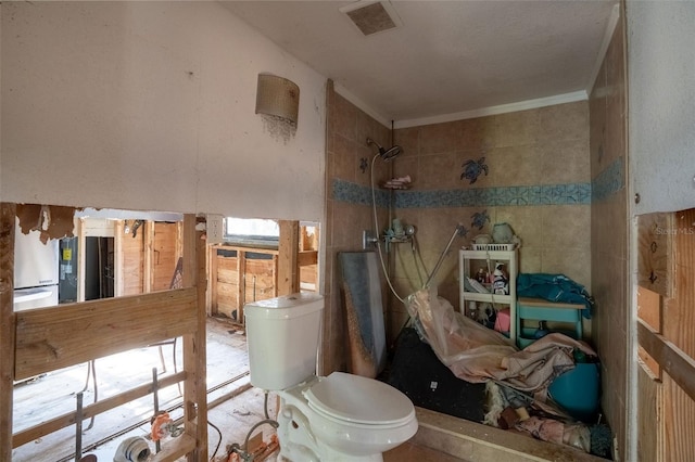 bathroom with crown molding, toilet, and a tile shower