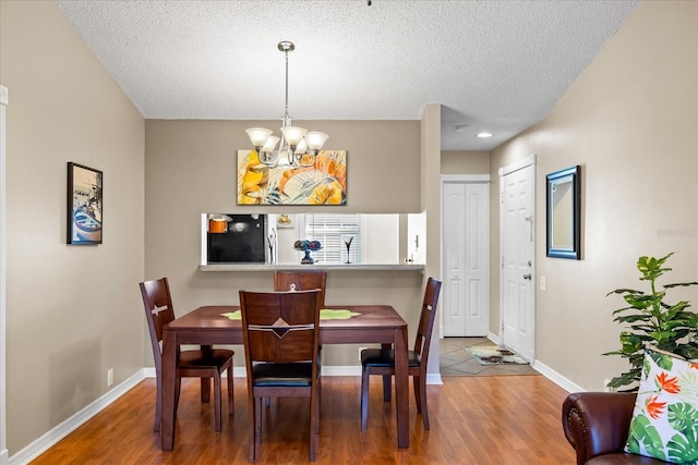 dining area featuring hardwood / wood-style floors, a textured ceiling, and a notable chandelier