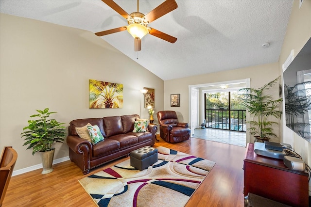 living room featuring ceiling fan, lofted ceiling, a textured ceiling, and light wood-type flooring